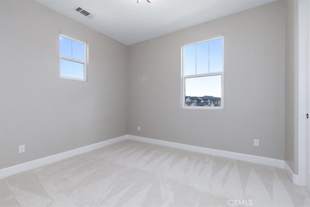 unfurnished room featuring baseboards, visible vents, and light colored carpet