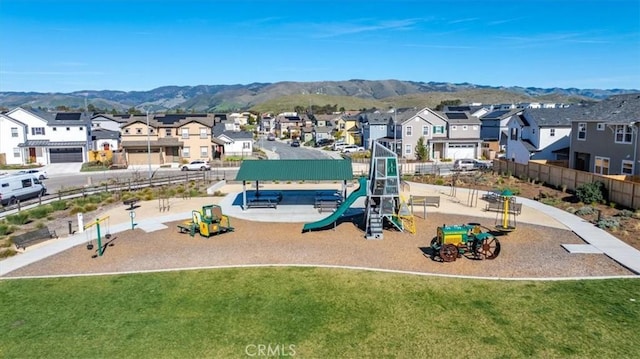 community playground with a residential view, a mountain view, fence, and a lawn