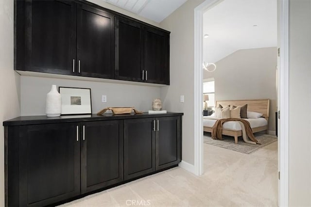 bar with vaulted ceiling, baseboards, and light colored carpet