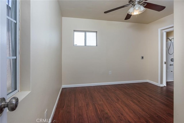 unfurnished room featuring dark wood finished floors, a ceiling fan, and baseboards