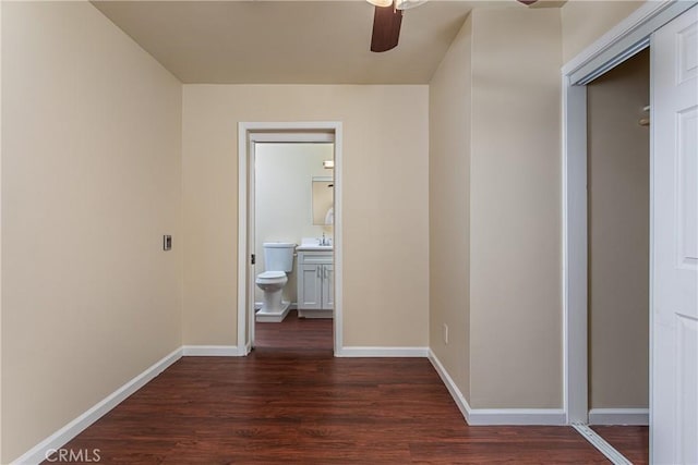 hallway featuring dark wood-style flooring, a sink, and baseboards