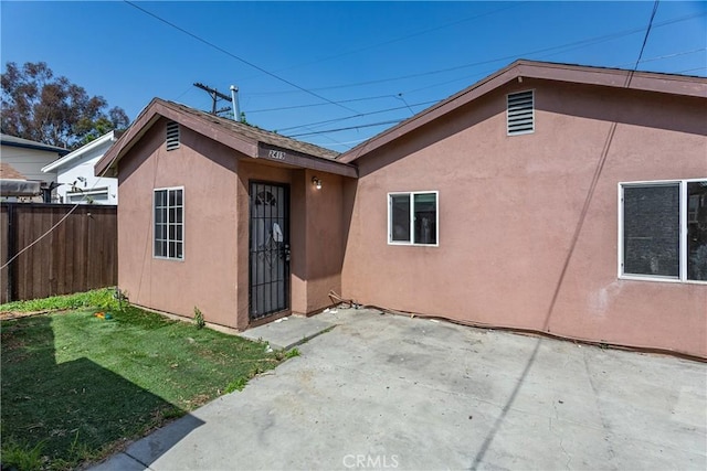 exterior space featuring a lawn, fence, a patio, and stucco siding