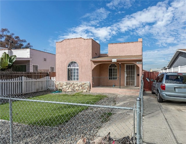 view of front of property featuring covered porch, a front lawn, a fenced front yard, and stucco siding