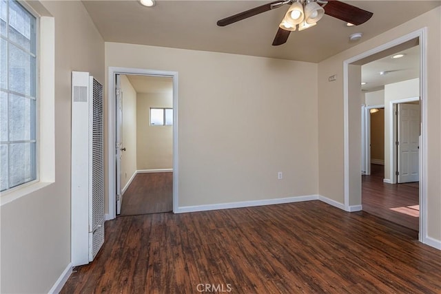 spare room with a ceiling fan, baseboards, a heating unit, and wood finished floors