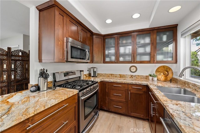 kitchen featuring appliances with stainless steel finishes, light stone counters, a sink, and recessed lighting