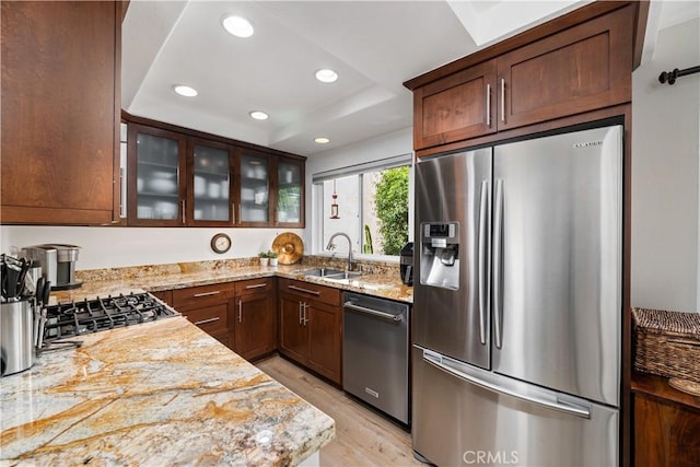 kitchen with light wood-style flooring, glass insert cabinets, stainless steel appliances, a sink, and recessed lighting