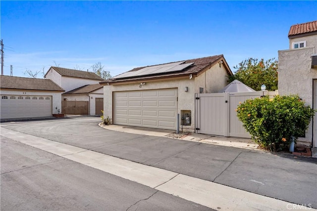 view of front of property featuring solar panels, fence, a gate, and stucco siding