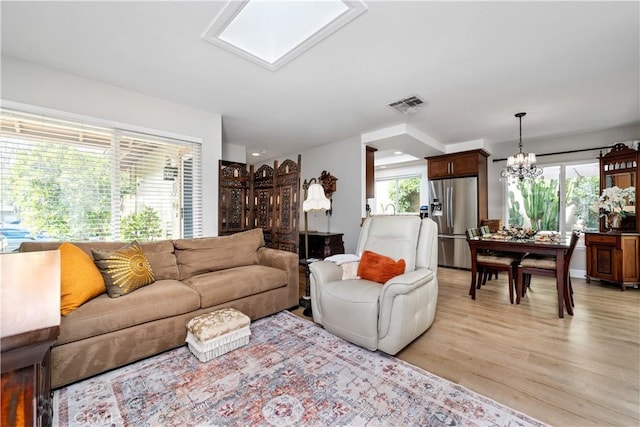 living room featuring a chandelier, visible vents, and light wood-style floors