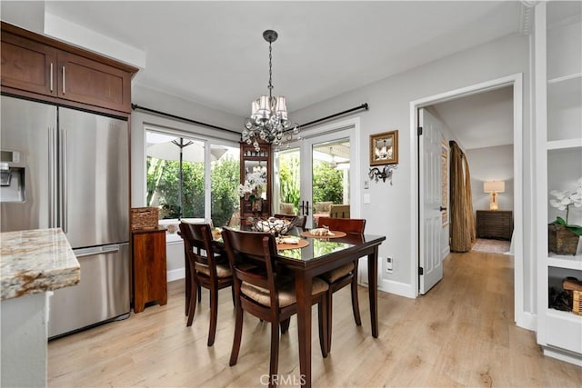 dining area with baseboards, light wood finished floors, and an inviting chandelier