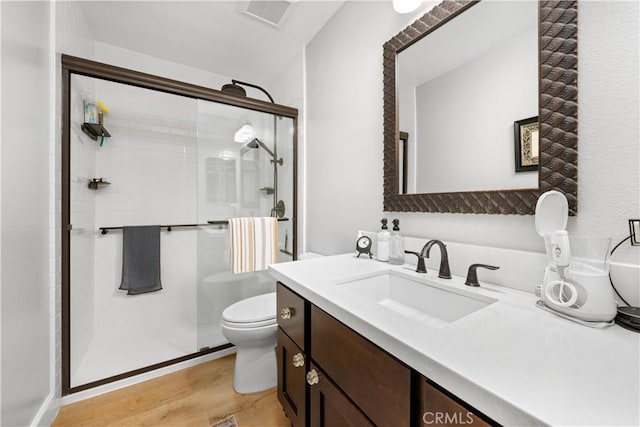 full bath with toilet, wood finished floors, vanity, visible vents, and a shower stall