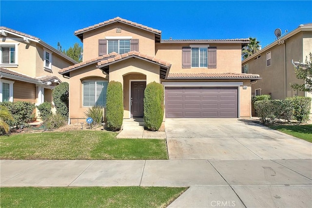 mediterranean / spanish house with driveway, a tiled roof, an attached garage, and stucco siding