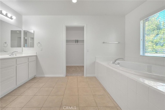 full bathroom with baseboards, a garden tub, tile patterned flooring, a walk in closet, and vanity