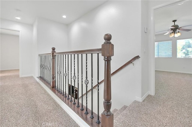 corridor featuring carpet, baseboards, and an upstairs landing