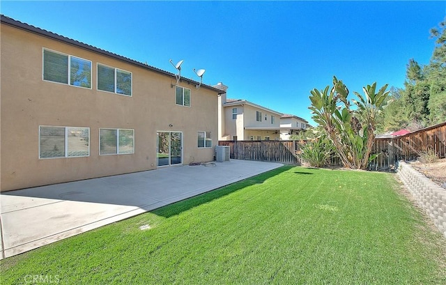 rear view of property featuring a lawn, a patio area, fence, and stucco siding