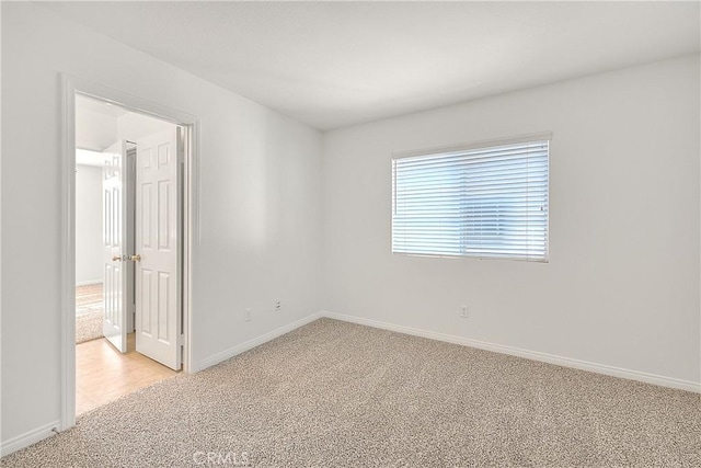 empty room featuring light carpet and baseboards