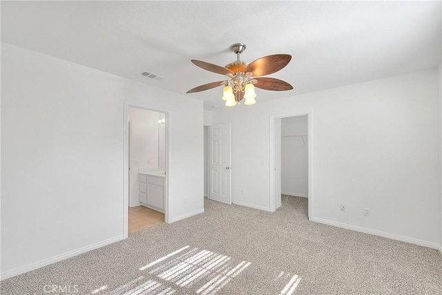 unfurnished bedroom with baseboards, a spacious closet, visible vents, and light colored carpet