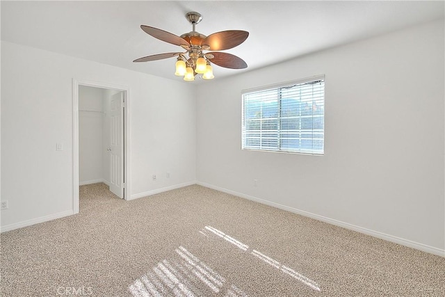 spare room featuring light carpet, ceiling fan, and baseboards