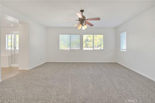 empty room with a ceiling fan, light colored carpet, baseboards, and light tile patterned floors