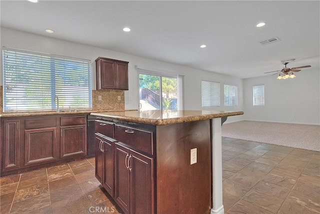 kitchen featuring light stone counters, visible vents, stone tile floors, and decorative backsplash