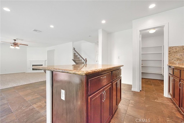 kitchen with a ceiling fan, recessed lighting, visible vents, and a fireplace