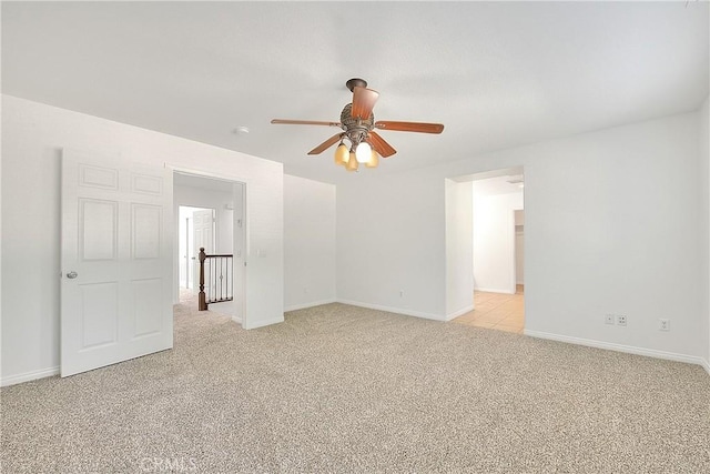 empty room with a ceiling fan, light carpet, and baseboards