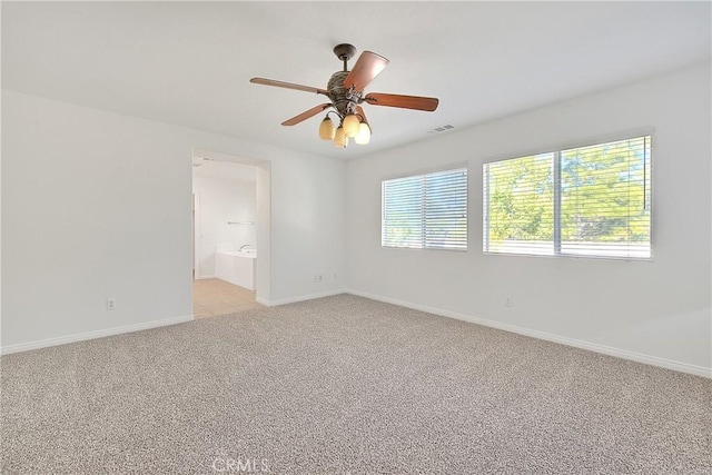 unfurnished room featuring a ceiling fan, light colored carpet, visible vents, and baseboards