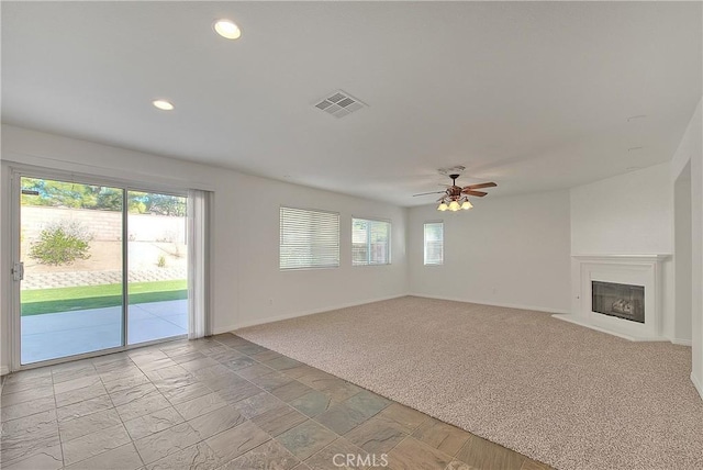 unfurnished living room featuring visible vents, a ceiling fan, light colored carpet, a fireplace with flush hearth, and recessed lighting