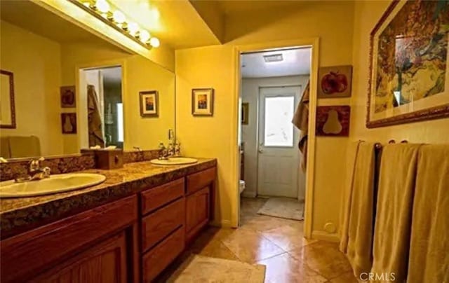 bathroom featuring double vanity, tile patterned flooring, a sink, and toilet