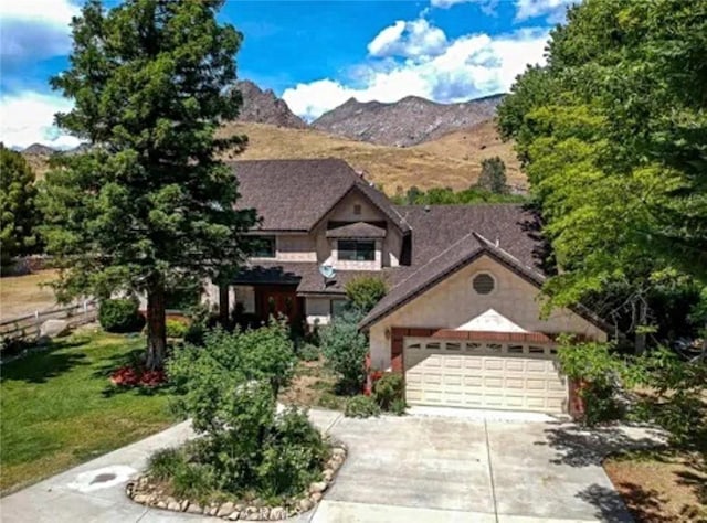 view of front facade with a front lawn, driveway, an attached garage, and a mountain view