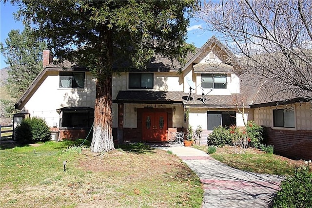 view of front facade with a front yard, french doors, and brick siding