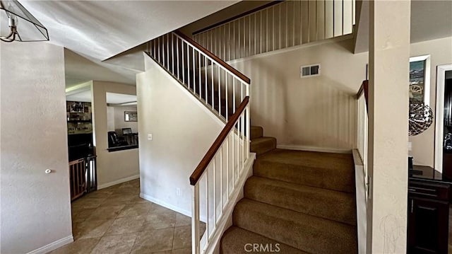 stairs featuring baseboards, visible vents, and tile patterned flooring