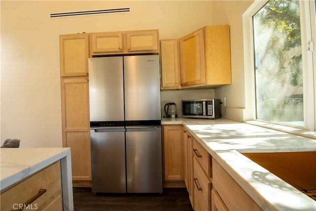 kitchen featuring stainless steel appliances, light brown cabinetry, dark wood-style flooring, and visible vents