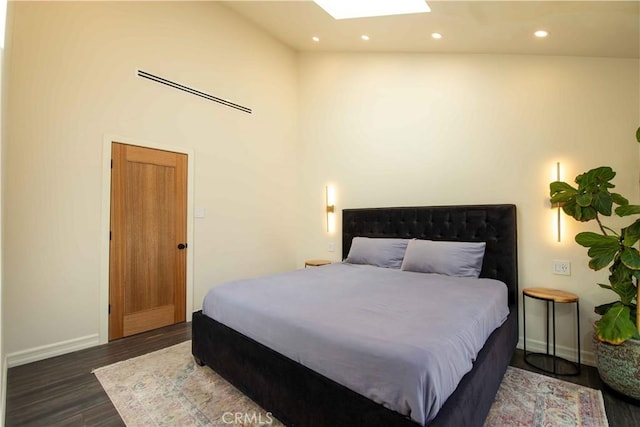 bedroom featuring recessed lighting, dark wood-style flooring, a skylight, a towering ceiling, and baseboards