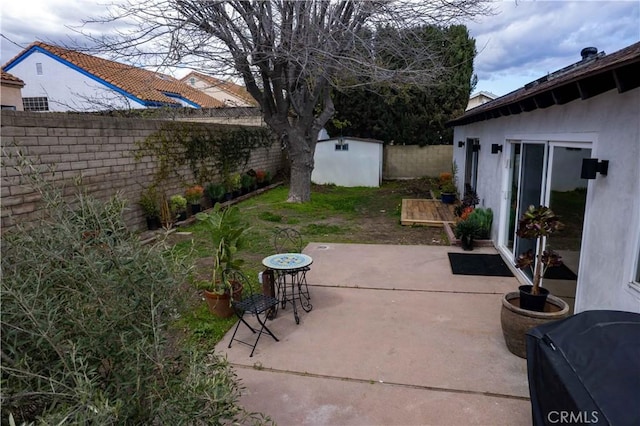 view of patio featuring an outbuilding, a storage unit, and a fenced backyard