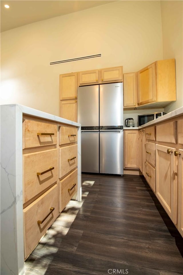 kitchen with light brown cabinets, dark wood finished floors, light countertops, and freestanding refrigerator