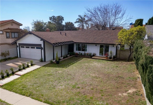 view of front facade with fence, a front yard, stucco siding, a garage, and driveway