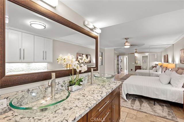 ensuite bathroom with crown molding, double vanity, connected bathroom, and stone tile floors