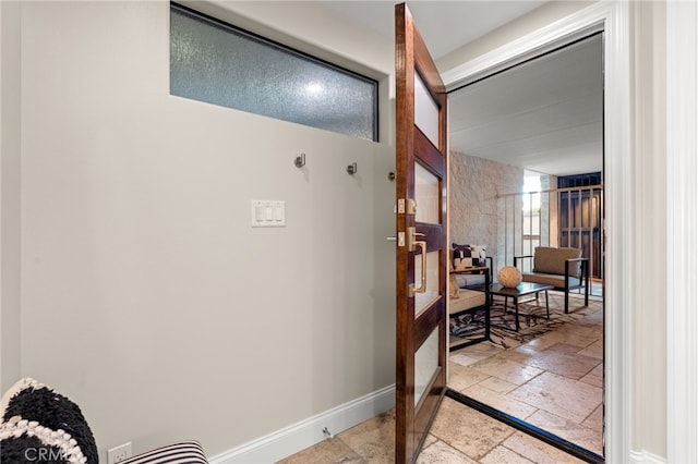 hallway with stone tile floors and baseboards