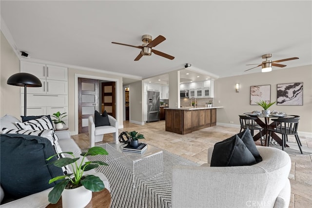 living area featuring a ceiling fan, baseboards, stone finish floor, and crown molding