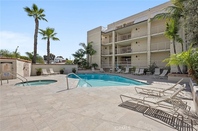 pool featuring a patio, a community hot tub, and fence