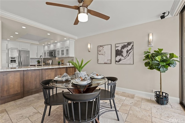 dining room featuring stone tile floors, baseboards, a tray ceiling, crown molding, and recessed lighting