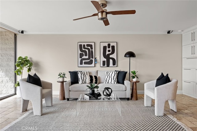 living room featuring a ceiling fan, crown molding, baseboards, and stone tile flooring