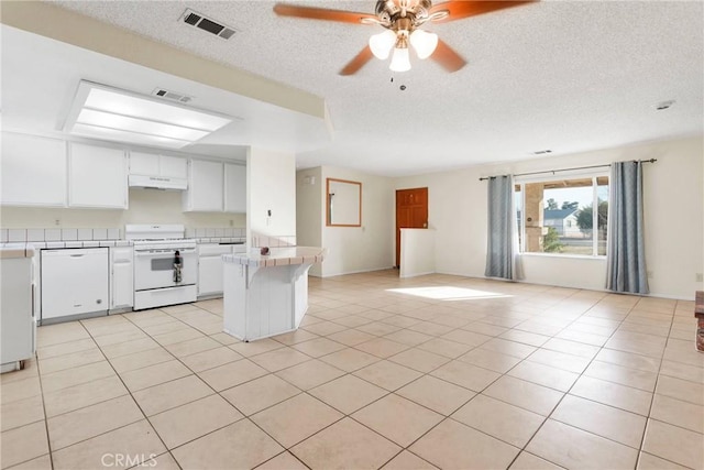 kitchen with visible vents, tile counters, open floor plan, white gas stove, and under cabinet range hood