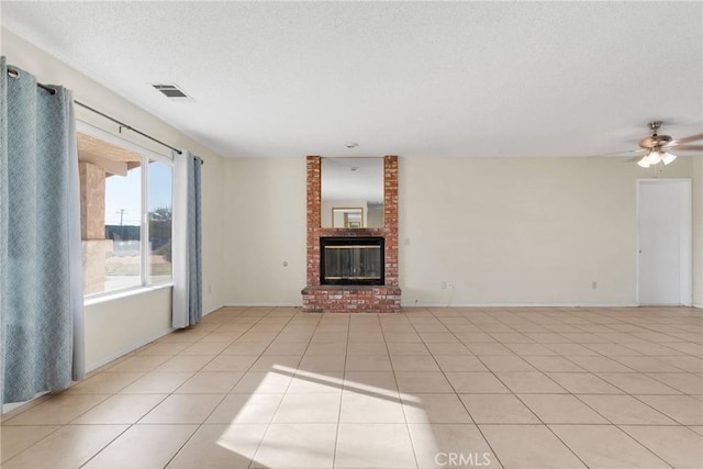 unfurnished living room with baseboards, visible vents, a textured ceiling, a fireplace, and light tile patterned flooring