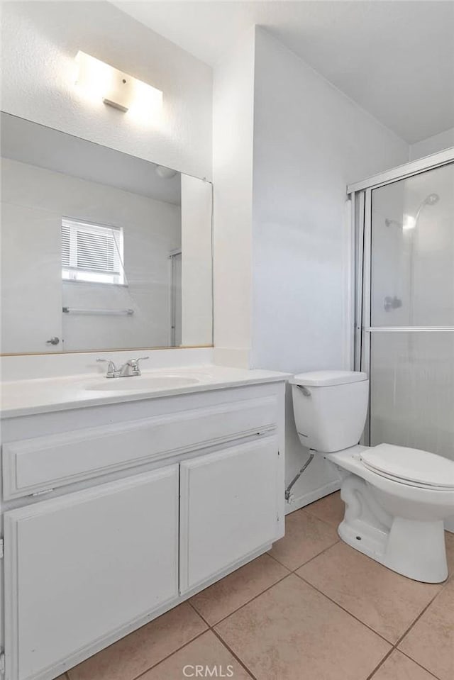 bathroom featuring tile patterned flooring, a shower stall, vanity, and toilet