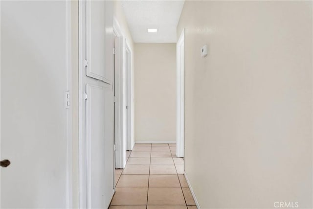 hallway with light tile patterned floors and baseboards