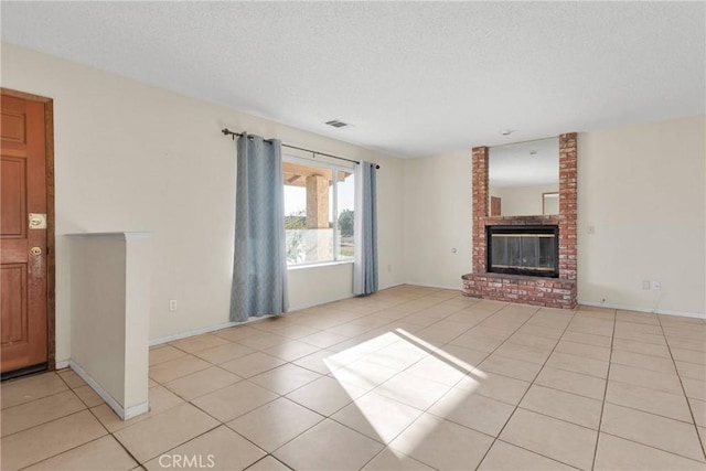 unfurnished living room with light tile patterned floors, baseboards, visible vents, a textured ceiling, and a brick fireplace