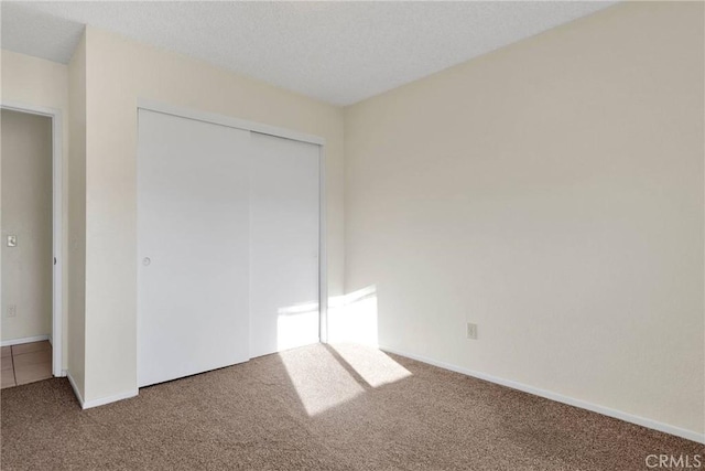 unfurnished bedroom with carpet floors, baseboards, and a closet