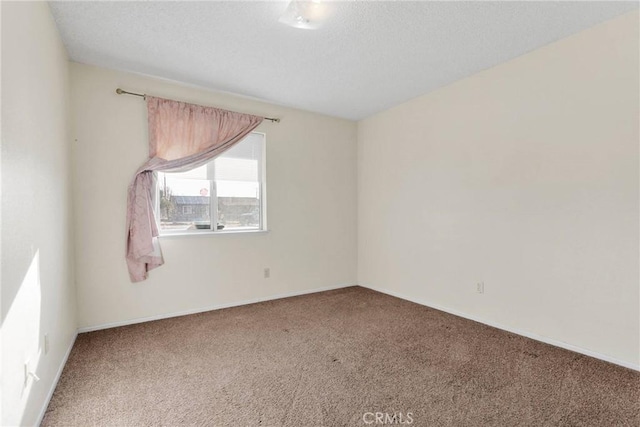 carpeted spare room featuring a textured ceiling and baseboards