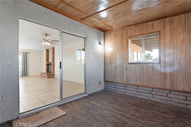 spare room with ceiling fan, wooden ceiling, a fireplace, and wood finished floors